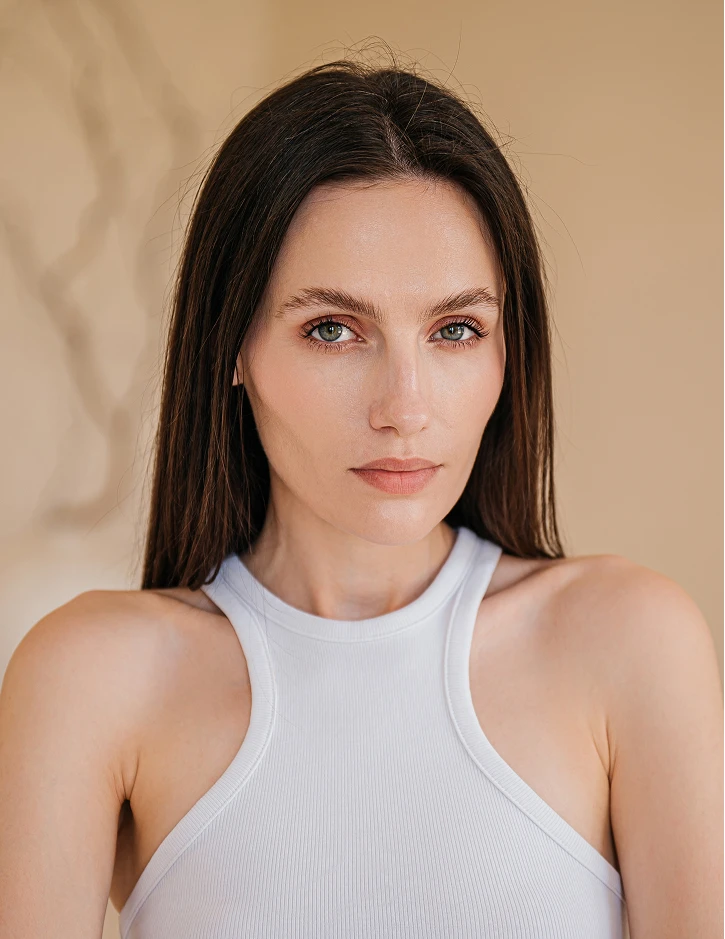 A women wearing a high white tank top and looking directly at camera, she has light eyes and straight brown hair. - Facelift in Santa Barbara, CA