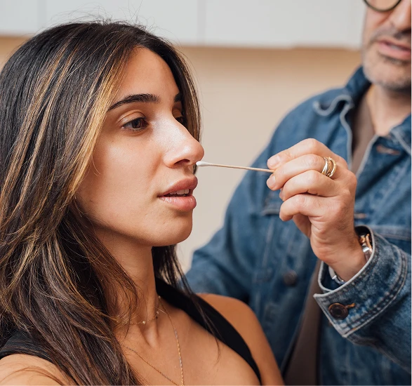 Dr. Moradzadeh, wearing a jean jacket, shown examining a patients nose with a cotton swab. - Sinus surgery in Santa Barbara, CA