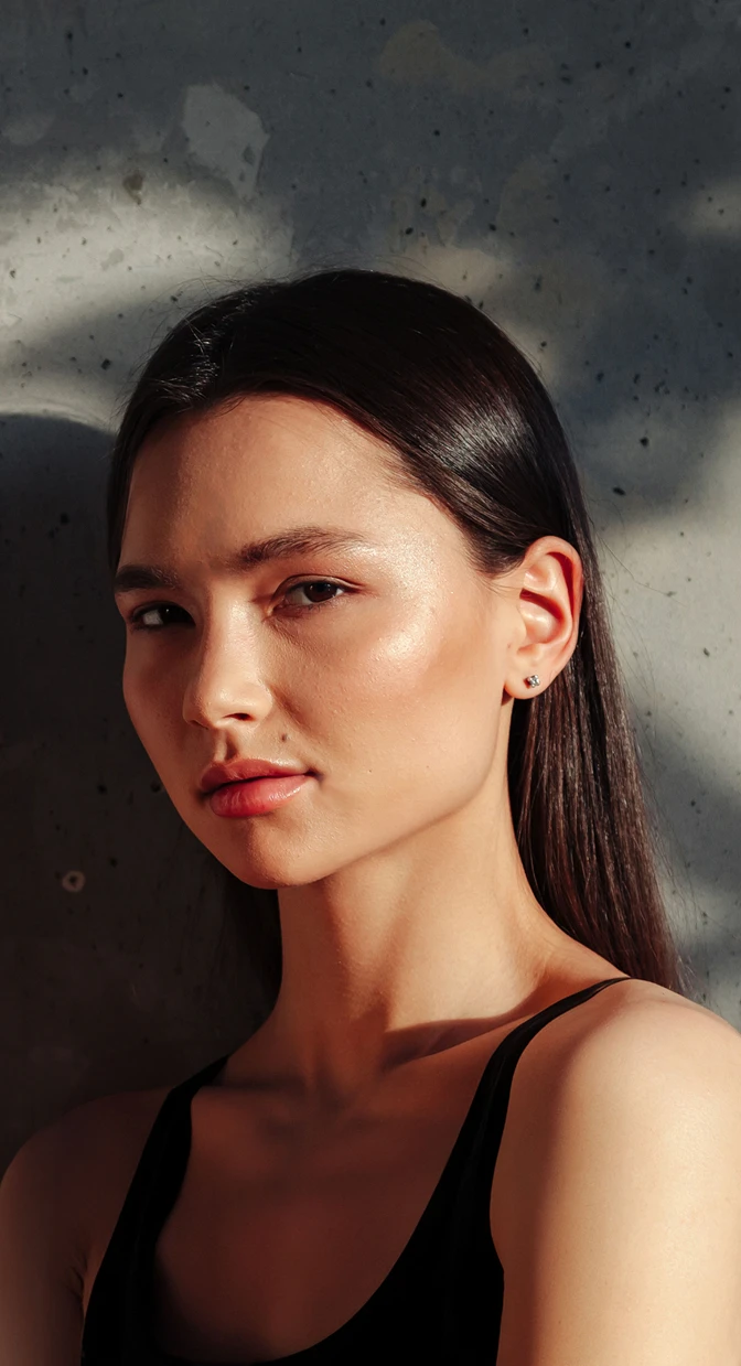A close up shot of a womens face. The women is wearing a black tank top and has a mole above her lip. She has straight dark brown hair and a serious look on her face. - Eye in Santa Barbara, CA