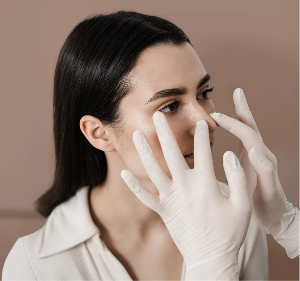 A women with straight black hair and s white button up shirt. Two hands with gloves are touching the women's nose. - Turbinate in Santa Barbara, CA