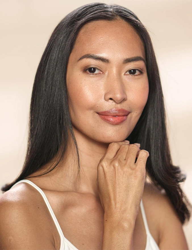A close up of a women's face as she puts her hand to her chin. She slightly smiles as she looks directly into the camera. She has straight black hair and is wearing a white tank top. - Ultraclear in Santa Barbara, CA