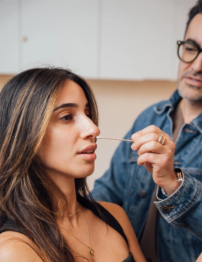Dr. Moradzadeh, wearing a jean jacket, shown examining a patients nose with a cotton swab. - Mini Rhinoplasty in Santa Barbara, CA